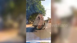 Reckless passenger clings onto metal pipes loaded onto back of truck