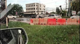 Traffic barriers float down road during flash floods in Thailand