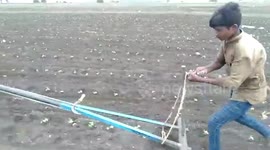 Farmer with one hand ploughs using his motorcycle and sprays pesticides in southern India