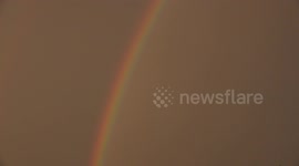 An Air Asia airplane flies through a rainbow.