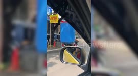 Motorcycle passenger in Indonesia rides with huge blue water tank over his body