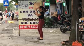 Vietnamese woman exercising with giant necklace while watching phone and holding conical hat in hand