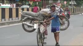 To save money man carries motorcycle on bicycle for 7km in north India