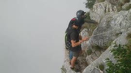 A pair of flying friends filmed themselves free falling from a cliff face hand in hand.