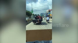 Passenger sits on the back of truck with his motorcycle
