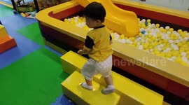 Diligent toddler knows to tidy up playground's balls