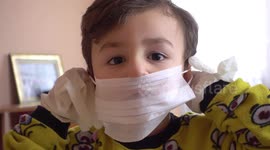 Cute little boy is bored and trying to have fun at home. He tries to entertain himself by playing with surgical masks and gloves