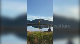 This stunning footage shows the moment a paraglider performs a ground spiral stunt perfectly reflected in the water below