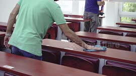 College staff disinfect an empty lecture hall, preparing the class for an exam during coronavirus pandemic