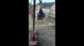 The worker desperately swings himself on the rope of the crane to move up the structure