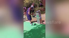 Chinese woman washes her child's feet in outdoor drinking fountain