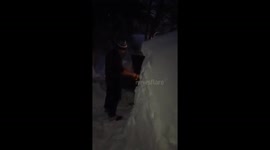 Man uses barbecue between huge snow drifts (looped)