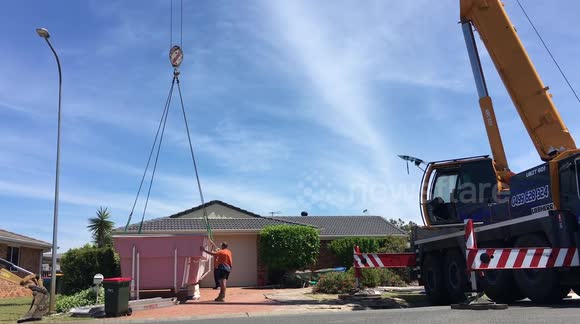 Crane lifts new pool over house and into position