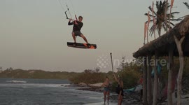 Up, up, and oh no! Kite surfer lands on the roof of a beach hut in Brazil