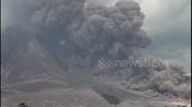 Indonesian locals gather to watch active volcano Sinabung spew thick ash into the air