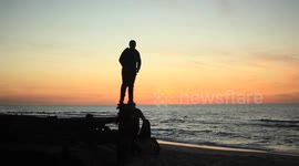 sunset and two young men jumping from rock