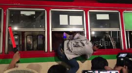 Thai protesters climb through bus being used as makeshift barricade outside Grand Palace