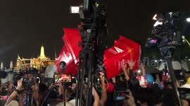 Protesters pass mock red postboxes containing letters to the Thai King