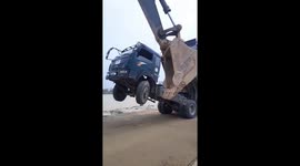 Transport truck tilts up onto back wheels while tipping rocks into river to prevent flooding in Vietnam