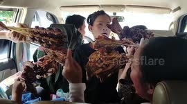 Street vendors surround family's car and thurst dozens of chicken kebabs through windows in Laos