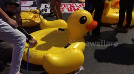 Thailand demonstrators carry wall of yellow rubber ducks
