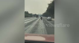 Reckless motorcycle rider seen steering with his feet while lying down