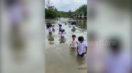 Schoolchildren wade through river to reach class