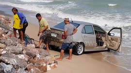 Teamwork! Beachgoers help to pull car from the sea in Thailand after driver crashed