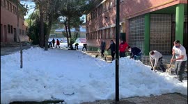 Families clean the snow from access to schools in Madrid 17th January, 2021.