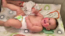Happy baby moving vigorously on his changing table, after discovering his arms and legs.