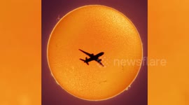 Aeroplane seen silhouetted dramatically in front of the sun as it crosses perfectly across the fiery surface