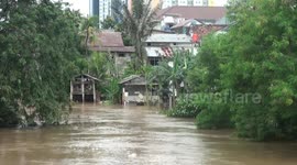 Teens play in river overflowing with floodwater in East Jakarta, Indonesia