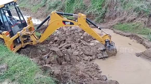 CAT MACHINE MAKING DRAIN AND REPAIRING ROAD