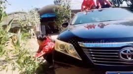 Chinese family shake tree branches beside car to make elderly man feel like he is driving