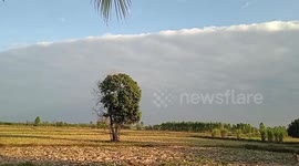 Long wall of cloud looms over village in Thailand