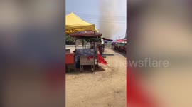 Dust devil tornado rips through dusty market in Thailand