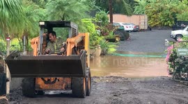 man clearing his driveway with caterpillar after heavy rain on oahu in hawaii