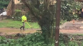 man clearing driveway with a shovel, flooding on oahu, falsh flood after heavy rain, people cleaning their property