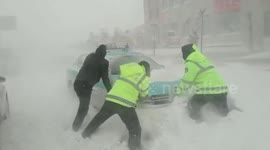 Police officers help push stranded vehicles as strong blizzard batters northern China