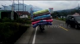 Biker in Indonesia wobbles terrifyingly as he transports huge pile of mattresses