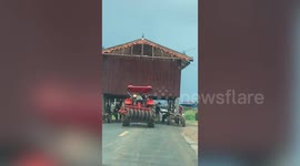 Cambodian villagers delay traffic as they transport entire house on tractor