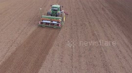 Tractor with attached sowing drill planting Flax, or Linseed in the fields of Northern France