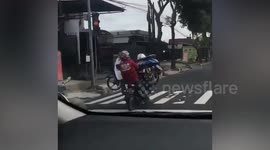 Rider and pillion passenger carry broken-down scooter between them