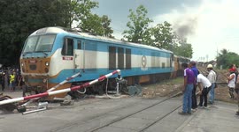 Train crashes through level crossing barrier in Thailand