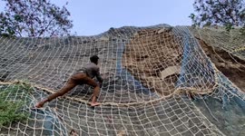 Rescuer climbs 20-foot-high netting at construction site to free trapped snake in India