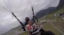 Pet dog wears goggles while enjoying windy paragliding ride with owner