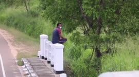 Duo of men sit on newly painted bridge fence while waiting for elephants in Sri Lanka
