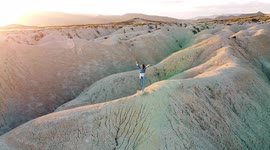 Mahoya desert drone point of view of woman standing over dunes at beautiful landscape against sunset.