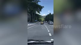 Badly damaged car overloaded with cargo drives along main road in Malaysia