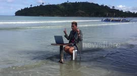 Dedicated Filipino teacher attends Zoom class while sitting on beach to get an Internet signal